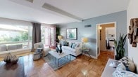 Located at 6200 W 3rd St in the heart of Los Angeles, this single-floor residence offers a thoughtfully designed layout with a cohesive coastal-inspired color palette throughout. The living room serves as the central gathering space, featuring warm parquet wood flooring, beamed ceilings, and soft blue-gray walls that create a calm, airy ambiance. Vibrant pink French doors open directly to an outdoor area, flooding the room with natural light and garden views. The space flows seamlessly into a dedicated dining area, where a ceiling fan, large windows, and bold botanical artwork set an inviting atmosphere. The kitchen is well-equipped with white cabinetry featuring glass-panel upper doors, granite-style countertops, a four-burner gas cooktop, and an over-the-range microwave. The bedroom is a restful retreat, highlighted by a teal accent wall, parquet flooring, a ceiling fan, and a window overlooking greenery. The bathroom features classic light-blue tile wainscoting, a pedestal sink, white wall cabinetry, and neutral mosaic tile flooring, contributing to the home's consistent coastal aesthetic. Throughout the residence, natural light, cohesive tones, and curated finishes create a welcoming and well-balanced living environment.
