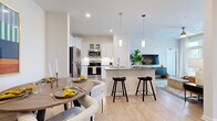 Located at 50 Fenway Place in Concord, NC, this thoughtfully designed single-floor residence offers a cohesive blend of modern finishes and functional living spaces throughout. The open-concept kitchen is a standout feature, showcasing white shaker cabinetry with glass-front upper cabinets, granite countertops, a peninsula with bar seating illuminated by pendant lighting, and a full suite of stainless steel appliances. Light wood-style flooring flows seamlessly from the kitchen through the dining area and into the living room, creating a unified, airy feel. The dining space comfortably accommodates a round table, while the living room features French doors that invite ample natural light and provide outdoor access. The primary bedroom is generously proportioned, benefiting from multiple windows and direct access to an en-suite bathroom. The primary bath offers a granite-topped vanity with white cabinetry and a walk-in glass-enclosed shower. A second bedroom provides comfortable accommodations, and a second full bathroom mirrors the same refined aesthetic with a granite vanity, white cabinetry, and a tub-shower combination. Recessed lighting, neutral wall tones, and consistent use of quality materials throughout lend the space a clean, contemporary ambiance well-suited for everyday living.