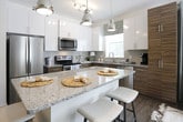 This single-floor residence at 2204 Duluth Highway 120 in Duluth, Georgia, showcases a contemporary design with an open-concept layout connecting the kitchen and living areas. The kitchen is a standout space, featuring granite countertops, a central island with bar seating, two-tone cabinetry combining white upper cabinets with warm wood-grain lower cabinets, stainless steel appliances, a subway tile backsplash, and pendant lighting overhead. Wood-look flooring flows throughout the main living areas, adding warmth and cohesion.

The living room is bright and inviting, benefiting from large windows and glass doors that open to a private balcony with outdoor views of surrounding greenery. A ceiling fan and sage-toned accent wall contribute to a relaxed yet modern ambiance.

Multiple bedrooms offer comfortable retreats, each with plush carpeting and ample natural light from large windows. One bedroom features direct access to an en-suite bathroom equipped with a walk-in shower, wood-grain vanity cabinetry, and granite countertops. A second full bathroom includes a tub-shower combination and matching wood-tone finishes. Floating shelves and thoughtful design details throughout the space add a polished, modern character.