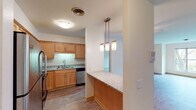 This single-floor residence offers a thoughtfully designed layout that balances function and comfort throughout. The kitchen is a standout feature, showcasing warm honey-toned cabinetry, granite countertops, and a classic subway tile backsplash. Stainless steel appliances—including a refrigerator, dishwasher, and microwave—complement the space, while a peninsula with pendant lighting provides a convenient breakfast bar and serves as a natural divide between the kitchen and the living area. The open living and dining area is finished with light hardwood-style flooring and receives natural light through a large window overlooking greenery outside. A ceiling fan adds practicality to the living space. The bedrooms are carpeted for comfort and each features windows that bring in natural light, along with closet storage. The hallway connects multiple rooms seamlessly, with built-in storage adding organizational convenience. The bathroom is finished with tile flooring and features a full tub and shower combination with tiled surround, along with a vanity and chrome fixtures. Neutral wall tones and clean lines throughout create a bright, move-in-ready atmosphere well-suited for a variety of living arrangements.