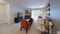 Located at 2411 Little Current Dr in Herndon, Virginia, this single-floor residence offers a thoughtfully laid-out interior with a variety of well-appointed living spaces. The living room is a welcoming focal point, featuring a fireplace, plush carpeted flooring, and a sliding glass door that opens to an outdoor area with views of surrounding greenery, allowing natural light to fill the room. A separate sitting room provides additional flexible living space, distinguished by a warm terracotta accent wall and a window that further brightens the area. The dedicated dining space accommodates a round glass-top table and features neutral wall tones, making it ideal for everyday meals or entertaining. The kitchen is equipped with white cabinetry, granite-style countertops, a stainless steel sink, and a gas range, offering a functional and clean workspace. The primary bedroom is generously sized with soft carpet, a serene color palette, and access to a spacious walk-in closet outfitted with wire shelving. An additional bedroom provides comfortable accommodations with ample room. The bathroom includes tile flooring, a vanity with granite-style counters and white cabinetry, a large mirror, and a shower-tub combination. Throughout the residence, a consistent use of neutral tones and carpet creates a cohesive and comfortable atmosphere.