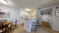 Located at 109 Raceway Pointe Dr in Daytona Beach, FL, this single-story, 2-bedroom, 2-bathroom home offers a well-designed layout across a comfortable footprint. The open-concept living area seamlessly connects the kitchen, dining room, and living room, creating a functional and social space. The kitchen features white cabinetry, light countertops, white appliances, and a peninsula with bar seating — ideal for casual dining. Adjacent to the kitchen, the dining area provides a dedicated space for seated meals. The living room is carpeted and benefits from a large window that invites natural light. The primary bedroom is a spacious retreat with a ceiling fan, a broad window with vertical blinds, and plush carpeting. The second bedroom also features a ceiling fan, a large window, and ample space for a desk or workspace. Both bathrooms are fitted with full tub-shower combinations and clean white tile surrounds. A dedicated in-unit laundry room features wood-look flooring and houses a full-size washer and dryer. The home also includes an entrance foyer and closets for each bedroom. The overall aesthetic is clean and neutral, with soft gray walls and light finishes throughout.