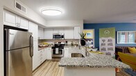 This single-story residence offers a thoughtfully designed layout with distinct living areas connected by light wood-style flooring. The kitchen serves as a functional centerpiece, featuring granite countertops, white shaker-style cabinetry, a classic subway tile backsplash, and a full suite of stainless steel appliances including a refrigerator, range, and built-in microwave. A peninsula with an undermount sink provides additional prep space and casual seating opportunities.

Adjacent to the kitchen, the dining area features a bold teal accent wall and wood-style flooring, creating a defined space for meals. The living room is bright and welcoming, with French doors that invite natural light and provide outdoor access, complemented by a ceiling fan and wood-style flooring.

The bedrooms feature plush carpet, generous windows with blinds and curtain panels, and ceiling fixtures. One bedroom showcases a vibrant yellow accent wall, while another features a softer green palette. The bathrooms include granite-topped white vanities, wood-style flooring, and a tub-shower combination. Walk-in closets with wire shelving provide organized storage. Overall, the space balances practical functionality with a colorful, contemporary aesthetic.