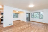 This single-floor residence offers a thoughtfully designed layout with a warm, cohesive aesthetic throughout. The living and dining areas are finished with light hardwood flooring that runs seamlessly through the main spaces, complemented by clean white walls and wood baseboards that lend a bright, welcoming ambiance. Large windows frame views of surrounding greenery, flooding the interior with natural light, while a sliding glass door provides direct access to a private balcony overlooking mature trees.

The kitchen is efficiently designed with warm honey-toned wood cabinetry, light countertops, and a full suite of stainless steel appliances, including a range, dishwasher, and built-in microwave. A wide entryway corridor connects the main living area to the kitchen and private rooms, creating a practical and open flow.

The bedroom is carpeted for added comfort and features a window with natural views, offering a quiet retreat. The bathroom includes a full soaking tub with shower, finished with clean white fixtures and wood-toned trim that ties into the overall design language of the unit. A dedicated entry area with a solid wood door completes the layout, providing a clear and functional transition into the home.