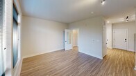 This 450 square foot apartment efficiently utilizes its single-floor layout to create a comfortable living space. The modern kitchen is a standout feature, boasting sleek white cabinetry that extends to the ceiling, maximizing storage. Stainless steel appliances, including a refrigerator, stove, and over-the-range microwave, add a contemporary touch. The kitchen's light-colored countertops contrast nicely with the wood-look flooring that runs throughout the apartment.

The bathroom continues the modern aesthetic with a floating wood-grain vanity, topped by a large mirror and contemporary lighting. A white sink and toilet maintain the clean, bright feel of the space. The main living area is open and versatile, with ample room for both living and sleeping arrangements. Large windows allow natural light to flood the space, creating an airy atmosphere. The apartment also includes a closet for additional storage.

The neutral color palette, dominated by whites and light wood tones, gives the apartment a fresh, spacious feel despite its compact size. Track lighting in the kitchen and living areas provides adjustable illumination. Overall, this apartment offers a well-designed, efficient living space that maximizes functionality without sacrificing style.