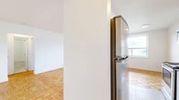 Located at 1050 Castlefield Ave, Unit 105, this well-appointed one-bedroom, one-bathroom unit offers a thoughtfully laid out single-floor plan. The living area is bright and open, showcasing classic parquet wood flooring in a basket-weave pattern and a large window that invites natural light while framing outdoor views. A radiator beneath the window provides reliable, traditional heating throughout the space.

The kitchen is a standout feature, designed in a galley style with white cabinetry extending to the ceiling, dark countertops, and a white subway tile backsplash. It is fully equipped with stainless steel appliances, including a refrigerator, electric range, and built-in microwave, complemented by marble-style flooring that ties the clean aesthetic together.

The bedroom is a comfortable size, continuing the parquet flooring found throughout the unit, and includes a built-in sliding door closet for ample storage. A window with an outdoor view and a radiator beneath it mirror the inviting feel of the living area.

The bathroom features classic white square wall tiles, a combined bathtub and shower with a curved curtain rod, a pedestal sink, and marble-style floor tiles, creating a clean and timeless finish. A hallway connects the rooms, completing this functional and well-designed unit.