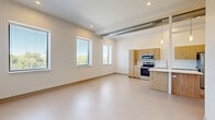 Located at 547 River St in Troy, NY, this modern 2-bedroom, 1-bathroom unit offers a clean, contemporary design across a single well-organized floor. The open-concept living, dining, and kitchen area forms the heart of the space, bathed in natural light from multiple windows with outdoor views of surrounding greenery. The kitchen is outfitted with light wood cabinetry, white quartz countertops, stainless steel appliances including a range, microwave, dishwasher, and refrigerator, as well as a peninsula island ideal for casual dining. An exposed duct detail adds an industrial loft character to the living area. Two hallways connect the private areas of the unit, leading to two carpeted bedrooms, each offering a quiet, comfortable retreat — one featuring a painted white brick accent wall. A versatile den provides additional flexible living space. The full bathroom features a wood-tone vanity with a white countertop, a tub-shower combination, and chrome fixtures. Four closets and a dedicated laundry area provide ample storage and convenience. Recessed lighting and a neutral color palette throughout give the space a bright, modern ambiance.