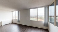 This single-floor, three-bedroom, two-bathroom residence in Little Rock, Arkansas offers a well-appointed layout with consistent dark hardwood-style flooring throughout. The open living area is defined by an abundance of natural light, drawn in through expansive sliding windows that frame elevated views of the surrounding landscape, including a nearby athletic track and tree-lined skyline. Vertical blinds provide privacy while preserving the airy feel of the space. Textured ceilings are present throughout, and ceiling fans in the bedrooms add comfort and functionality.

The kitchen has been thoughtfully updated with white shaker-style cabinetry, granite-look countertops, a classic white subway tile backsplash, and a stainless steel gas range. The bedrooms are generously sized with clean white walls and ample natural light from large windows offering outdoor views. The bathrooms feature modern finishes, including a floating vanity with a white vessel-style sink and framed mirror, as well as a full tub-shower combination with white subway tile surround. The overall aesthetic is clean, bright, and contemporary throughout.