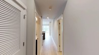 Located at 4525 Guadalupe St in Austin, Texas, this single-floor space offers a clean, modern aesthetic defined by crisp white walls, light wood flooring, and an efficient, well-organized layout. A central hallway serves as the spine of the space, connecting the various rooms with a sense of flow and openness. Recessed lighting overhead and natural light filtering in from windows keep the interiors bright and welcoming throughout.

The layout reveals a thoughtfully arranged floor plan visible from the overhead view, with distinct zones for living, working, and utility functions. The living area is generously proportioned, featuring the warm light wood flooring that carries through much of the space. A compact kitchen area includes dark appliances and counter space, positioned to take advantage of natural light from a nearby window.

Additional rooms branch off the central corridor, offering private spaces that maintain the same consistent palette of neutral tones and light finishes. The bathroom is neatly tucked into the layout, and a ceiling fan in one of the rooms adds both function and comfort. Throughout the space, the design emphasizes simplicity and practicality, with white trim, recessed lighting, and minimalist finishes contributing to an overall atmosphere that is bright, clean, and move-in ready.