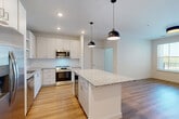 This well-appointed 2-bedroom, 1-bathroom residence in Peabody, MA offers a thoughtfully designed open-concept layout with modern finishes throughout. The kitchen serves as the centerpiece of the home, showcasing crisp white cabinetry, granite countertops, a subway tile backsplash, and a full suite of stainless steel appliances including a refrigerator, range, microwave, and dishwasher. A generously sized center island with matching granite provides additional prep space and casual seating, while stylish black pendant lights add a contemporary touch. Light hardwood flooring runs seamlessly through the kitchen and living areas, creating a warm, cohesive feel. The living area benefits from natural light through large windows and direct access to an outdoor balcony. Both bedrooms feature plush carpeting and windows that bring in natural light, with the primary bedroom offering a comfortable and spacious retreat. The bathroom is finished with a granite-topped vanity, white cabinetry, and modern hardware. Ample storage is provided through four closets, including a walk-in with built-in shelving. A dedicated laundry area adds everyday convenience, completing this well-rounded and move-in-ready home.