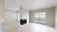 This single-floor residence offers a thoughtfully designed layout centered around a bright, open-concept living area. The main living space is finished with light hardwood-style flooring and features a striking corner fireplace with a classic white surround and mantel, serving as the room's focal point. Crown molding adds a refined architectural detail, while multiple windows dressed with horizontal blinds fill the space with abundant natural light.

The kitchen is well-equipped and functional, featuring gray shaker-style cabinetry, white countertops, a stainless steel sink with a modern pull-down faucet, a stainless steel dishwasher, and a subway tile backsplash. A peninsula counter connects the kitchen to the living area, creating a seamless open flow ideal for entertaining.

The bedrooms are carpeted for comfort and include ceiling fans and windows that bring in natural light. The bathroom is finished consistently with the rest of the home, featuring gray cabinetry, white countertops, a framed mirror, and light hardwood-style flooring. A dedicated in-unit laundry room includes a full-size washer and dryer with overhead wire shelving for added storage convenience. Throughout, a cohesive palette of soft grays, whites, and warm neutrals creates a calm and inviting atmosphere.