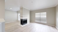 This single-floor residence offers a thoughtfully designed layout centered around a bright, open-concept living area. The main living space is finished with light hardwood-style flooring and features a striking corner fireplace with a classic white surround and mantel, serving as the room's focal point. Crown molding adds a refined architectural detail, while multiple windows dressed with horizontal blinds fill the space with abundant natural light.

The kitchen is well-equipped and functional, featuring gray shaker-style cabinetry, white countertops, a stainless steel sink with a modern pull-down faucet, a stainless steel dishwasher, and a subway tile backsplash. A peninsula counter connects the kitchen to the living area, creating a seamless open flow ideal for entertaining.

The bedrooms are carpeted for comfort and include ceiling fans and windows that bring in natural light. The bathroom is finished consistently with the rest of the home, featuring gray cabinetry, white countertops, a framed mirror, and light hardwood-style flooring. A dedicated in-unit laundry room includes a full-size washer and dryer with overhead wire shelving for added storage convenience. Throughout, a cohesive palette of soft grays, whites, and warm neutrals creates a calm and inviting atmosphere.