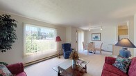 This single-floor residence offers a well-organized layout designed for comfortable everyday living. The living room serves as the heart of the home, featuring wall-to-wall carpeting, a textured ceiling, and a large picture window fitted with vertical blinds that allow generous natural light and views of the surrounding greenery. A sliding glass door connects the living area to an adjacent dining space, which is illuminated by track lighting overhead and benefits from its own window with outdoor views — creating a bright and pleasant area for meals. The galley-style kitchen is efficiently arranged with white cabinetry, ample counter space, a coil electric range, and a dishwasher, with patterned tile flooring and a ceiling light fixture. The entry foyer, accessible from the kitchen, features the same tile flooring and provides a practical transition into the home. Two carpeted bedrooms offer comfortable retreats, each with windows that bring in natural light. The bathroom includes a single-sink vanity with built-in cabinetry, a large mirror, and tile flooring. A dedicated utility closet houses the water heater and includes built-in shelving for additional storage. Baseboard heating is present throughout, providing consistent warmth across the unit.