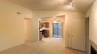 This single-floor residence offers a welcoming and functional layout centered around an open-concept living and dining area. The living space is finished with plush wall-to-wall carpeting that extends throughout the main areas, creating a warm and comfortable atmosphere. A ceiling fan provides both comfort and ambient lighting to the central gathering space.

The kitchen is conveniently positioned in an open, semi-partitioned nook, fitted with warm wood-toned cabinetry and equipped with a stainless steel range and matching appliances. An overhead range hood and track lighting add practical functionality to the space. The entryway features durable tile flooring, providing a clean transition from the exterior into the home.

A standout feature of this residence is the sliding glass door that opens directly to a private outdoor deck or patio area, allowing natural light to pour into the living space and offering a seamless connection to the outdoors. The textured ceilings and neutral wall tones throughout lend the space a classic, understated character. Track lighting in the entryway and ceiling fan fixtures ensure the unit is well-lit throughout. Overall, the layout is efficient and cohesive, making excellent use of the available space while maintaining an open, airy feel.