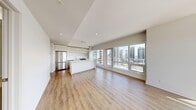 Located in Calgary, AB, this modern 1-bedroom, 1-bathroom unit offers a thoughtfully designed open-concept layout with a clean, contemporary aesthetic throughout. Light-toned hardwood flooring runs seamlessly across the living, kitchen, and bedroom areas, complementing the crisp white walls and bright, airy atmosphere.

The combined kitchen and living area forms the heart of the unit. The kitchen is outfitted with full-height white cabinetry, a large central island with a quartz countertop, stainless steel appliances including a French door refrigerator and range, and a tiled backsplash. Floor-to-ceiling windows on two sides of the living area flood the space with natural light and deliver sweeping panoramic views of the Calgary skyline and surrounding cityscape.

The bedroom is a well-proportioned, serene retreat featuring large windows that continue the city views and fill the room with abundant sunlight. The clean, neutral palette of the room provides a calm and functional space.

The bathroom features large-format beige floor tiles, a soaking tub with an overhead shower, white tile surround, a white vanity with integrated countertop, and recessed lighting, completing the modern and cohesive design of the unit.