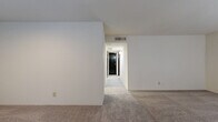 This 2-bedroom, 2-bathroom single-floor home offers a practical and well-organized layout designed to maximize everyday comfort. The living room features neutral carpet flooring and crisp white walls, opening to a hallway that connects the main living area to the private sleeping quarters. The galley-style kitchen is outfitted with warm wood cabinetry, granite-look countertops, a double stainless steel sink, and durable hardwood-style flooring, providing ample storage and counter space for cooking and meal prep. Both bathrooms are finished consistently, each featuring a tub-shower combination with white tile surround, wood vanity cabinetry with matching countertops, and tile flooring. The primary bedroom is a comfortable size, enhanced by a large window that fills the room with natural light and soft carpet underfoot. The second bedroom also features carpet and a ceiling fan, adding to its versatility. A notable storage highlight is the spacious walk-in closet equipped with wire shelving systems on multiple walls, offering generous organization capacity. Two additional closets throughout the home further enhance storage options. The space maintains a clean, neutral palette throughout, creating a move-in-ready environment with a cohesive and practical aesthetic.