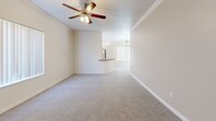 This single-story, 3-bedroom, 2-bathroom home offers a thoughtfully designed layout that maximizes comfort and functionality. The open-concept living room and kitchen area serves as the heart of the home, featuring plush carpeting, crown molding, and a ceiling fan with light fixture. Natural light filters through vertical blinds on large windows, creating a bright and airy atmosphere. A pendant chandelier accents the dining area adjacent to the kitchen.

The kitchen is well-equipped with light wood cabinetry, bold dark marble-style countertops, and a full suite of stainless steel appliances including a gas range, microwave, dishwasher, and refrigerator. A peninsula with matching countertop provides additional prep space and connects the kitchen to the living area. Hexagonal tile flooring completes the kitchen's modern aesthetic.

Each of the three bedrooms features soft carpeting, ceiling fans, and generous windows with vertical blinds. Bedrooms include sliding panel closets for ample storage. The primary bedroom offers a notably spacious footprint.

Both bathrooms are finished consistently with dark marble-style countertops, wood-toned vanity cabinetry, hexagonal tile flooring, and tub-shower combinations. A dedicated laundry room houses a full-size washer and dryer with overhead shelving for added convenience.
