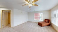 This single-floor residence offers a thoughtfully arranged layout with a bright and open living area at its heart. The living room is generously proportioned, finished with plush wall-to-wall carpeting, and equipped with a ceiling fan to enhance comfort. Multiple windows fitted with slatted blinds allow natural light to fill the space while providing privacy, and views of the surrounding exterior add a sense of connection to the outdoors.

The kitchen is efficiently designed with white cabinetry, granite-style countertops, and white appliances including a coil-burner electric range, an over-the-range microwave, and a full-size refrigerator — all from Whirlpool. The kitchen opens toward the main living area, supporting an easy flow between cooking and living spaces. Hardwood-style flooring grounds the kitchen zone, contrasting with the carpeted areas throughout the rest of the unit.

The bedrooms are carpeted and well-lit, each featuring windows with blinds, clean neutral walls, and individual wall-mounted heating units for climate control. The bathroom includes a full soaking tub and shower combination with a clean, white surround and light wood-toned door detailing. A hallway connects all areas of the unit, and a dedicated entry door provides a clear threshold into the space. Overall, the residence presents a clean, functional, and comfortable living environment.