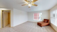 This single-floor residence offers a thoughtfully arranged layout with a bright and open living area at its heart. The living room is generously proportioned, finished with plush wall-to-wall carpeting, and equipped with a ceiling fan to enhance comfort. Multiple windows fitted with slatted blinds allow natural light to fill the space while providing privacy, and views of the surrounding exterior add a sense of connection to the outdoors.

The kitchen is efficiently designed with white cabinetry, granite-style countertops, and white appliances including a coil-burner electric range, an over-the-range microwave, and a full-size refrigerator — all from Whirlpool. The kitchen opens toward the main living area, supporting an easy flow between cooking and living spaces. Hardwood-style flooring grounds the kitchen zone, contrasting with the carpeted areas throughout the rest of the unit.

The bedrooms are carpeted and well-lit, each featuring windows with blinds, clean neutral walls, and individual wall-mounted heating units for climate control. The bathroom includes a full soaking tub and shower combination with a clean, white surround and light wood-toned door detailing. A hallway connects all areas of the unit, and a dedicated entry door provides a clear threshold into the space. Overall, the residence presents a clean, functional, and comfortable living environment.
