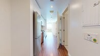 Unit 1203 at 6245 Wilshire Blvd is a 430-square-foot studio condominium located on the 12th floor in the heart of Los Angeles' Miracle Mile neighborhood. The unit features warm hardwood flooring throughout the main living areas, crisp white walls, and recessed lighting that lend a clean, contemporary aesthetic. The open-plan living space is bathed in natural light and offers expansive city views through floor-to-ceiling sliding glass doors that open to the outside, creating a bright and airy atmosphere. The galley-style kitchen is well-appointed with stainless steel appliances including a gas range and microwave, warm wood cabinetry, white upper cabinets, a herringbone tile backsplash, and a sleek countertop with an undermount sink. A dedicated closet area houses a stacked in-unit washer and dryer, adding everyday convenience. The bathroom features large-format cream tile flooring, a glass-enclosed shower, a floating wood vanity with a white countertop and integrated sink, a full-width mirror, and modern chrome fixtures. The unit's efficient layout maximizes every square foot, making it an ideal urban residence in one of Los Angeles' most sought-after corridors.