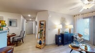 This single-story residence offers a thoughtfully designed layout that balances comfort and functionality throughout. Light wood-style flooring flows seamlessly across the main living areas, creating a cohesive and inviting atmosphere.

The living room serves as the heart of the home, featuring a ceiling fan, large sliding glass doors that invite natural light and provide direct patio access, and ample space for relaxed seating arrangements. A decorative accent wall adds character to the room.

The kitchen is well-equipped with dark cabinetry, granite-style countertops, stainless steel appliances including a refrigerator, range, and microwave, and a peninsula breakfast bar with pendant lighting overhead — ideal for casual dining or entertaining. A dedicated hallway connects the living spaces to the private areas of the home.

Two bedrooms offer comfortable retreats, each featuring wood-style flooring, ceiling fans, and windows that allow natural light to filter in. The rooms provide generous space for full bedroom furnishings.

The bathroom is clean and functional, featuring a full tub-shower combination, wood-style flooring, and recessed lighting. A dedicated entryway corridor with recessed lighting and closet access rounds out this well-organized and move-in-ready home.