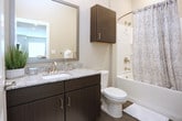 Located at 6840–6846 Governors West NW in Huntsville, Alabama, this single-floor unit features a contemporary open-concept design that seamlessly connects the kitchen and living areas. The kitchen is well-appointed with dark espresso cabinetry extending to the ceiling, stainless steel appliances including a refrigerator, electric range, and microwave, and a granite-topped island with an undermount sink that provides additional prep and seating space. Wood-style plank flooring runs throughout the main living areas, contributing to a clean, modern aesthetic.

The spacious living area benefits from multiple windows that invite abundant natural light and is equipped with a ceiling fan. Bedrooms are carpeted for comfort and feature large windows, providing bright and versatile spaces. The bathroom includes dark cabinetry, granite countertops, a framed mirror, and wall-mounted lighting, with an adjoining walk-in closet outfitted with built-in shelving and hanging rods. A dedicated laundry area houses a full-size Whirlpool washer and dryer. Throughout, neutral-toned walls, white trim, and recessed lighting create a cohesive and contemporary atmosphere.