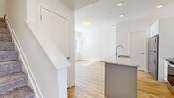 Located at 1901 S Hover Street in Longmont, Colorado, this thoughtfully designed two-story home offers two bedrooms and one bathroom spread evenly across two floors. The main level features a bright, open-concept layout with light wood-look flooring throughout. The kitchen is a standout, boasting white shaker cabinets, granite countertops, a white subway tile backsplash, and stainless steel appliances including a refrigerator, range, and over-the-range microwave. A central island with a granite surface and undermount sink doubles as a prep and casual dining space, anchoring the kitchen to the adjacent living area. A staircase connects the two floors, maintaining an open, airy feel. Upstairs, both bedrooms are carpeted and bathed in natural light from large windows with views of the surrounding area. Each bedroom includes a closet, providing practical storage. The bathroom is finished with the same attention to detail found throughout the home, featuring a dual-sink granite vanity with blue-gray cabinetry, wood-look flooring, and a window for natural light. The home's clean white walls, modern fixtures, and cohesive material palette create a fresh, contemporary ambiance throughout.