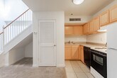 Located at 1351 W Broad St in Richmond, Virginia, this two-floor unit offers a practical and straightforward layout across its multiple levels. The main living area features warm, neutral-toned carpet underfoot and soaring walls that lend a sense of openness to the space. A classic staircase with white balusters and a wood handrail connects the two floors, with convenient storage tucked neatly beneath it. A louvered door nearby adds a touch of traditional detail to the interior.

The kitchen is well-equipped with warm honey-toned wood cabinetry extending to the upper and lower walls, providing ample storage. It includes a double-basin sink, generous laminate countertops, a coil-element range, and a black dishwasher, all set on easy-to-clean tile flooring that also flows through the entryway.

Upstairs, a spacious room showcases a distinctive exposed wood beam ceiling, giving the space a rustic, characterful ambiance, with soft carpeting below and clean white walls throughout.

The full bathroom is finished with light tile flooring, a wood-vanity with a single sink, a mirror, and a combination tub and shower, maintaining a clean and functional aesthetic consistent with the rest of the unit.