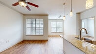 Located at 8355 Braesmain Dr in Houston, TX, this single-story, one-bedroom, two-bathroom residence offers a well-designed layout that maximizes its comfortable footprint. An elegant arched entryway connects the hallway to the open-concept living and kitchen area, setting a welcoming architectural tone throughout. The combined living and kitchen space is bright and airy, featuring warm hardwood-style flooring, multiple windows dressed with blinds that invite abundant natural light, and a ceiling fan for added comfort. The kitchen is a functional centerpiece, showcasing granite countertops, warm wood cabinetry, black appliances including a range and refrigerator, a double-basin sink set in a peninsula island, and stylish pendant lighting complemented by track lighting overhead. The spacious primary bedroom continues the hardwood-style flooring and includes a ceiling fan, a large window with outdoor views, and access to a generous walk-in closet with built-in wire shelving. A second closet with open shelving provides additional storage. Both bathrooms feature tile flooring, with one offering a soaking tub surrounded by neutral stone-tiled walls. A dedicated laundry room with tile flooring accommodates a full-size washer and dryer, adding everyday convenience. The overall ambiance is clean, neutral, and move-in ready.