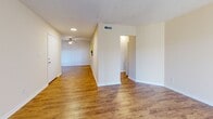 This single-story, one-bedroom, one-bathroom unit at 3913 Pisa Dr in Panama City, Florida, offers a efficiently organized layout with distinct living spaces connected by a central hallway. The combined kitchen and living area forms the heart of the unit, featuring warm wood-look flooring throughout. The living room benefits from a large sliding glass door dressed with vertical blinds, allowing natural light to fill the space. A ceiling fan adds functionality to the living area, while a textured ceiling provides additional visual detail.

The kitchen is designed for practicality, featuring white cabinetry with ample upper and lower storage, light-toned countertops, a double-basin stainless steel sink, and white appliances including a range and built-in microwave. A pass-through window connects the kitchen to the adjacent space, enhancing the open feel.

The bedroom is carpeted for comfort and includes a dedicated closet with louvered bifold doors. A sliding glass door with vertical blinds provides natural light and outdoor access. The full bathroom is accessible from the bedroom area and features a white tub and shower unit with built-in shelving and chrome fixtures. Neutral, warm beige tones are consistent throughout the unit, creating a cohesive and clean aesthetic.