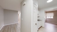 Located at 401 Connor Ct in Schenectady, NY, this single-floor, 2-bedroom, 2-bathroom unit offers a clean, modern aesthetic throughout. Light-toned laminate wood flooring extends across the living areas and bedrooms, contributing to a bright, cohesive look. Neutral gray walls complement the light palette, creating a calm and functional environment.

The kitchen features white cabinetry, granite-style countertops, a double stainless steel sink with brushed nickel fixtures, and a white dishwasher. A connecting hallway links the kitchen to the rest of the unit. Two living room areas provide flexible use of space for both lounging and dining arrangements.

Both bedrooms receive natural light through windows with blinds. The primary bedroom is a comfortable size with ample wall space, while the second bedroom also benefits from a window with an exterior view. A dedicated closet includes built-in wire shelving systems for organized storage.

The two bathrooms feature light ceramic tile flooring, white vanities, and stainless steel grab bars, indicating accessibility-conscious design. The overall layout, connected by a central hallway, ensures an efficient and practical flow throughout the unit.