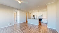 Located in Orlando's vibrant Ivanhoe Village neighborhood, this well-appointed one-bedroom, one-bathroom residence offers a thoughtfully designed open-concept layout filled with abundant natural light. Wide-plank hardwood-style flooring flows throughout the main living areas, complementing the clean, contemporary aesthetic.

The kitchen is a standout feature, showcasing white shaker cabinetry extending to the ceiling, a marble-style tile backsplash, sleek quartz countertops, a center island with a built-in sink, and a full suite of stainless steel appliances including a refrigerator, range, microwave, and dishwasher.

The living room is bright and airy, anchored by floor-to-ceiling sliding glass doors that open directly onto a private balcony, offering open city views and abundant sunlight. A ceiling fan adds both function and style.

The bedroom is a comfortable retreat with plush carpeting, a tray ceiling, mirrored closet doors, and its own set of expansive glass sliding doors leading to the balcony. The bathroom features wood-look tile flooring, a sleek walk-in glass-enclosed shower with textured wall tile, and clean white finishes throughout. A dedicated closet and hallway complete this well-organized residence.
