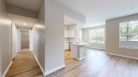 Located at 1000 Fanfare Way in Alpharetta, Georgia, this single-floor residence offers a well-designed open-concept layout with contemporary finishes throughout. The living area is bright and airy, featuring wood-style plank flooring, a ceiling fan, and a large window that brings in abundant natural light and views of surrounding greenery. A graceful arched passageway connects the living space to the entryway, while built-in shelving provides convenient display and storage options.

The kitchen is a standout feature, outfitted with white shaker-style cabinetry, a classic subway tile backsplash, white quartz countertops, and a full suite of stainless steel appliances including a refrigerator, range, and over-the-range microwave. A peninsula with an integrated sink adds functional workspace and serves as a natural divider between the kitchen and living areas.

The bedrooms are finished with plush carpeting and ceiling fans, with windows offering pleasant outdoor views. The primary bathroom includes a white vanity with quartz countertops, a framed mirror, and direct access to a spacious walk-in closet with built-in shelving. A dedicated laundry area with a full-size washer and dryer rounds out this thoughtfully appointed home.
