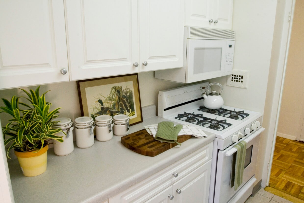 Kitchen with white countertop, white cabinetry, white appliances and hard surface flooring - Eaves Glover Park