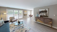 Located at 1900 Chestnut Ave in Glenview, Illinois, this single-floor residence offers a well-organized layout with distinct living spaces connected by a cohesive, neutral design palette. The open living and dining area is anchored by light wood-style flooring, large windows, and French doors that invite abundant natural light and provide access to an outdoor area. A dedicated dining nook features warm-toned hardwood floors and a statement pendant light fixture, creating an intimate setting for meals. The galley-style kitchen is outfitted with white shaker cabinetry, quartz countertops, a mosaic tile backsplash, stainless steel appliances, and a deep undermount sink, opening toward a casual dining space with additional window views. The primary bedroom is generously proportioned with plush carpeting, soft neutral walls, and large windows dressed in sheer curtains. A second bedroom with vaulted ceilings offers flexibility as a guest room or home office, complemented by natural light and carpeted floors. Both bathrooms are updated with white vanities, quartz surfaces, and wood-look luxury vinyl flooring. One bathroom features a tub-shower combination, while the other offers a streamlined walk-in shower layout. Throughout the home, a calm, neutral color scheme and consistent finishes contribute to a polished and welcoming ambiance.