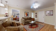 This single-floor, 2-bedroom, 2-bathroom residence offers a thoughtfully organized layout that maximizes comfort and functionality. The open-concept living and dining area is anchored by warm hardwood flooring, crown molding, and ceiling fans that lend a classic, polished character throughout. The living room provides ample space for seating, accented by a decorative area rug, framed artwork, and a dedicated media corner. Natural light filters in through several windows, creating a bright and welcoming ambiance.

The kitchen features white cabinetry, light countertops, and full appliances including a range, built-in microwave, and dishwasher. A pass-through window connects the kitchen to the dining and living areas, enhancing the open feel of the space.

Both bedrooms are carpeted for comfort and include ceiling fans, windows with outdoor views, and ample closet space. The primary bedroom is generously sized with a walk-in closet equipped with built-in shelving and hanging rods. The second bedroom is equally comfortable with good natural light.

The two bathrooms are clean and functional, with one featuring a tiled tub-shower combination, white cabinetry, and hardwood flooring. A hallway connects the bedrooms and bathrooms, completing this efficiently designed and move-in-ready home.