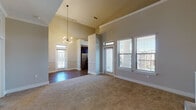 This single-floor residence is defined by its dramatic vaulted ceilings and an open, airy layout that creates a strong sense of volume throughout. The expansive living area is anchored by a sleek fireplace set against towering walls, with plush carpeting underfoot and an abundance of natural light streaming through multiple windows fitted with blinds. A stylish pendant chandelier adds a modern focal point, while a sliding door provides direct access to an outdoor balcony with neighborhood views.

The kitchen is thoughtfully designed with rich dark cabinetry, granite countertops, a classic subway tile backsplash, stainless steel appliances, and wood-look flooring — combining both function and aesthetic appeal. An overhead linear light fixture illuminates the space efficiently.

The bedrooms are generously sized, each featuring carpet flooring, ceiling fans, and ample natural light. The primary bedroom includes a spacious walk-in closet, offering excellent storage. The en-suite primary bathroom is well-equipped with a dual-sink vanity topped with granite, dark wood cabinetry, framed mirrors, wood-look flooring, and a glass-enclosed walk-in shower. A second bathroom offers a full tub-shower combo with clean, bright finishes and additional cabinetry for storage.