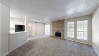 Located at 2401 W Spring Creek Pkwy in Plano, TX, this single-floor residence offers 2 bedrooms and 3 bathrooms within a well-organized, comfortable layout. The welcoming entrance opens through a hallway with wood-look flooring that transitions into the spacious combined living and dining area. The living room is a standout, anchored by a striking floor-to-ceiling brick fireplace and complemented by plush carpeting, a textured ceiling, and multiple windows that invite natural light. Adjacent to the living area, the kitchen features white cabinetry, light countertops, a double sink, and a window above — along with a pantry for added storage convenience. The primary bedroom is generously sized, complete with a ceiling fan, carpeted flooring, and access to a walk-in closet with built-in shelving and hanging rods. The second bedroom also features a ceiling fan and carpeted floors. Three bathrooms are distributed throughout the home, each with wood-look vinyl flooring, white vanities with light countertops, and mirrors. A dedicated laundry area and five closets in total ensure ample storage. The textured ceilings and neutral color palette throughout create a cohesive, move-in ready atmosphere well-suited for comfortable everyday living.