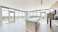 Located at Harbor Point in Stamford, CT, this thoughtfully designed 2-bedroom, 2-bathroom residence offers a refined living experience with modern finishes and breathtaking water views. Light wood-tone flooring runs throughout the space, creating a warm and cohesive aesthetic.

The open-concept kitchen and living area serves as the heart of the home. The kitchen is outfitted with stainless steel appliances, warm wood cabinetry with textured detail, white quartz countertops, a subway tile backsplash, and a central island ideal for dining or entertaining. Track lighting adds a contemporary accent overhead.

The living area is bathed in natural light, thanks to expansive floor-to-ceiling windows that frame sweeping panoramic views of the waterfront and surrounding greenery—a defining feature of this residence.

The generously sized primary bedroom offers direct access to a well-appointed en-suite bathroom, complete with a sleek double vanity featuring an illuminated mirror, grey cabinetry, light wood-tone flooring, and a frameless glass-enclosed shower. A dedicated closet provides ample storage.

The second bedroom is bright and versatile, featuring a sliding closet and neutral walls. The second bathroom is efficiently designed with a vanity, illuminated mirror, and shower-tub combination. Throughout, the clean, neutral palette creates a calm and inviting atmosphere.