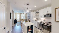 Located at 120 Whitby Lane in Birmingham, Alabama, this well-appointed one-bedroom, one-bathroom residence offers a smart, efficient layout across a single floor. The open-concept design connects the kitchen, living room, and hallway seamlessly, creating a cohesive and functional living environment.

The kitchen is a standout feature, outfitted with white shaker cabinetry, a subway tile backsplash, quartz countertops, stainless steel appliances — including a French door refrigerator, range, microwave, and dishwasher — and a central island with seating, illuminated by statement glass pendant lights.

The living room is bright and welcoming, featuring wood-look flooring, a ceiling fan, recessed lighting, and a glazed door that opens to a private balcony overlooking the resort-style pool and landscaped courtyard below.

The bedroom is a comfortable retreat with plush carpet, a ceiling fan, and windows that invite natural light. The full bathroom offers wood-look flooring, a marble-surround soaking tub and shower combination, a white vanity with a large mirror, and matte black hardware throughout.

The hallway connects all rooms efficiently, completing a residence that balances modern design with practical livability in a well-maintained community setting.