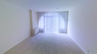 This two-floor space offers a clean and functional layout with a neutral aesthetic that creates a bright and welcoming atmosphere. The interior is characterized by crisp white walls and soft, light-toned carpeting that adds warmth underfoot while maintaining a simple, understated look throughout.

A standout feature of the main living area is the expansive floor-to-ceiling window dressed with vertical blinds, which allows an abundance of natural light to flood the room. The generous glazing creates a luminous environment and offers the potential for pleasant outdoor views. A baseboard heating unit is neatly positioned beneath the window, ensuring comfort throughout the seasons.

The room itself is spacious and open, providing considerable flexibility for furniture arrangement and use of space. The smooth white ceilings and uncluttered walls contribute to an airy, minimalist feel that suits a variety of interior styles.

Spread across two floors, the overall layout provides distinct zones for living, working, or other functional needs, with the multi-level design offering separation and versatility. The consistent use of neutral tones and simple finishes across the space creates a cohesive and calm atmosphere, making it an adaptable environment well-suited to a range of uses.