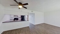 This single-story space is designed with a clean, functional layout that maximizes the available square footage. The open-concept living and dining area flows directly into the kitchen, creating a cohesive and connected main living space. Wood-look laminate flooring runs consistently throughout, lending a warm, unified aesthetic to every room. A ceiling fan with a built-in light fixture is installed in the living area, complementing the textured popcorn ceiling overhead.

The kitchen features white cabinetry paired with dark countertops and a classic white subway tile backsplash that extends to the cooking area. Black appliances, including a range and refrigerator, provide a crisp contrast to the lighter cabinetry. A peninsula-style counter separates the kitchen from the living space, offering a practical divide while maintaining the open feel.

The bedrooms are well-proportioned, each equipped with windows that bring in ample natural light and views of the surrounding exterior. The bedroom walls are painted white, maintaining the bright, neutral palette found throughout the unit.

The bathroom is outfitted with a full soaking tub and shower combination, accented by white subway tile surround. Wood-look tile flooring ties the bathroom's design to the rest of the space. Overall, the unit presents a cohesive, freshly updated interior with a clean and practical aesthetic.