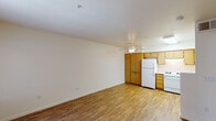 This single-floor unit offers a practical and well-organized layout across its main living areas. The living room is bright and open, featuring durable wood-style flooring, neutral cream-toned walls, and a ceiling fan that enhances airflow and comfort. A window with vertical blinds allows natural light to filter in, and a front entry door provides convenient access directly into this welcoming space.

The kitchen flows seamlessly from the living area and is well-equipped with warm oak-toned cabinetry offering generous storage, light countertops, a white gas range, a refrigerator, a dishwasher, and a double-basin stainless steel sink. A large pantry-style cabinet provides additional storage, and a ceiling-mounted light fixture ensures the workspace is well-lit.

The bedroom is finished with plush carpeting and neutral walls, creating a comfortable retreat. A window looks out to a fenced outdoor area with greenery, bringing in natural light and a sense of connection to the exterior.

The bathroom is efficiently laid out, featuring a wood-vanity with a single sink, a lighted mirror, a combination tub and shower with grab bars, and wood-style flooring that ties in with the rest of the unit. The overall ambiance is clean, functional, and move-in ready.