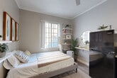 This 160 square foot studio apartment in Los Angeles offers a thoughtfully designed living space that maximizes functionality in a compact footprint. The interior showcases a modern aesthetic with a clean, neutral color palette and light wood-tone flooring throughout, creating a bright and airy ambiance.

The main living area serves as a multifunctional space, featuring a comfortable bed, strategically placed shelving, and a television for entertainment. A large window allows natural light to flood the room, enhancing the sense of spaciousness. The kitchenette, while compact, is well-equipped with white cabinetry, stainless steel appliances, and a sleek countertop, providing all essentials for basic meal preparation.

The bathroom, though small, is efficiently designed with a modern vanity, mirror, and necessary fixtures. Its all-white design contributes to a clean and fresh appearance. Clever storage solutions and minimalist decor throughout the apartment help maintain a clutter-free environment, making the most of the limited square footage.

Despite its size, the apartment doesn't compromise on style, featuring touches of modern decor such as framed artwork, plants, and a statement yellow armchair that adds a pop of color to the neutral palette. This studio is an excellent example of how thoughtful design can transform a small space into a comfortable and inviting home.