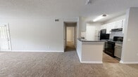 Located in Hoover, Alabama, this one-bedroom, one-bathroom unit offers a well-organized single-floor layout designed for comfortable everyday living. The open-concept living area is a standout feature, anchored by a tile-surround wood-burning fireplace and a bay window configuration that allows ample natural light to fill the carpeted space. A ceiling fan overhead and a glass-paned entry door add to the room's functionality and brightness.

The kitchen is positioned adjacent to the living area and is defined by a peninsula with a dark countertop that doubles as a breakfast bar. White upper cabinetry contrasts with gray lower cabinets, and the kitchen is equipped with a black electric range, a stainless steel refrigerator, and wood-look plank flooring that extends throughout the cooking space.

A hallway connects the living area to the private bedroom, which features plush carpeting, a ceiling fan with light fixture, a closet, and direct access to the full bathroom. The bathroom includes a vanity with dark countertops and gray cabinetry, a large mirror, a tub-shower combination, and wood-look flooring, completing this efficiently designed unit.