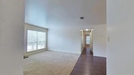 Located at 9250 Dean Rd in Shreveport, Louisiana, this single-story home offers a practical and well-organized layout across three bedrooms and two bathrooms. The living room serves as a welcoming central space, featuring a wood-burning fireplace, a large window that allows natural light to fill the room, and a combination of dark hardwood-style flooring and plush carpeting. A hallway connects the living area to the rest of the home, leading to the bedrooms beyond. The galley-style kitchen is efficiently designed with warm wood cabinetry, light countertops, dark hardwood-style flooring, and black appliances including a refrigerator and microwave, complemented by a double sink and dishwasher. The primary bedroom is a generously sized retreat with carpet flooring and a spacious walk-in closet outfitted with wire shelving and hanging rods for ample storage. The additional bedrooms are carpeted and include ceiling fans for comfort. Both bathrooms are well-appointed, featuring wood vanities with stone-look countertops, tile flooring, and tub-shower combinations. The home's clean, neutral palette and thoughtful layout provide a versatile and comfortable living environment.