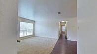 Located at 9250 Dean Rd in Shreveport, Louisiana, this single-story home offers a practical and well-organized layout across three bedrooms and two bathrooms. The living room serves as a welcoming central space, featuring a wood-burning fireplace, a large window that allows natural light to fill the room, and a combination of dark hardwood-style flooring and plush carpeting. A hallway connects the living area to the rest of the home, leading to the bedrooms beyond. The galley-style kitchen is efficiently designed with warm wood cabinetry, light countertops, dark hardwood-style flooring, and black appliances including a refrigerator and microwave, complemented by a double sink and dishwasher. The primary bedroom is a generously sized retreat with carpet flooring and a spacious walk-in closet outfitted with wire shelving and hanging rods for ample storage. The additional bedrooms are carpeted and include ceiling fans for comfort. Both bathrooms are well-appointed, featuring wood vanities with stone-look countertops, tile flooring, and tub-shower combinations. The home's clean, neutral palette and thoughtful layout provide a versatile and comfortable living environment.