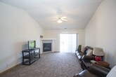 This single-floor unit offers a well-organized layout designed for comfortable everyday living. The living room serves as the central gathering space, highlighted by a vaulted ceiling with a ceiling fan, a corner gas fireplace, and a sliding glass door that opens to a balcony, allowing natural light to fill the room. The open arrangement connects seamlessly to the dining area, which features carpet flooring and a six-panel entry door, accommodating a standard dining table setup.

The galley-style kitchen is efficiently designed with white cabinetry, white appliances including an electric range and dishwasher, and tile flooring. A doorway at the end of the kitchen leads directly to a dedicated laundry area housing a full-size washer and dryer, adding practical convenience.

The unit includes two carpeted bedrooms, each offering adequate space and neutral wall tones. One bedroom features a large window with vertical blinds providing natural light. Both rooms offer easy access to the bathrooms. The bathrooms are finished with tile flooring, white vanities with wood-trimmed cabinetry, and a shower-tub combination. Overall, the unit maintains a clean, neutral aesthetic throughout.