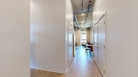 Located at 2650 University Ave SE in Minneapolis, this modern unit offers four bedrooms and four bathrooms across a single floor, designed with a clean, contemporary aesthetic ideal for student or shared living. The open-concept living, dining, and kitchen area serves as the heart of the unit, featuring light wood-tone flooring, exposed concrete ceilings with visible ductwork that lend an industrial character, and recessed track lighting. The kitchen is equipped with white cabinetry, stainless steel appliances including a refrigerator, stove, and microwave, and a functional layout that flows seamlessly into the dining and living areas. Each of the four bedrooms is a private suite with its own en-suite bathroom, offering comfort and privacy for each resident. The bathrooms are finished with light wood-tone flooring, white walls, and warm wood vanity cabinetry. Several bedrooms feature large windows that frame views of the surrounding Minneapolis neighborhood, filling the rooms with natural light. Exposed concrete columns add to the architectural character throughout. Two hallways, two closets, and a dedicated laundry area round out the practical layout, making this a well-appointed, efficiently designed unit close to the University of Minnesota campus.