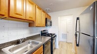 This single-floor residence offers a well-organized layout that balances functionality and comfort throughout its interior. The galley-style kitchen is efficiently designed, featuring warm honey-toned wood cabinetry, dark granite-look countertops, and a classic white subway tile backsplash. Black appliances, including a gas range, built-in microwave, dishwasher, and refrigerator, provide a cohesive look, while a stainless steel double sink adds practicality. Light wood-style luxury vinyl flooring runs through the kitchen and connects seamlessly to the hallway and main living areas.

The living room is notably open and bright, benefiting from sliding glass patio doors fitted with vertical blinds that allow natural light to fill the space and provide access to an outdoor area with exterior views. The same light flooring continues throughout, contributing to a clean, airy ambiance.

The bedrooms are carpeted in neutral tones and each includes a closet for storage, with windows that bring in additional natural light. The bathroom is finished with white subway tile wainscoting, grey floor tile, a white vanity with an integrated sink, an over-mirror medicine cabinet, and a lighted vanity mirror, creating a clean and functional space. A hallway connects all rooms cohesively.